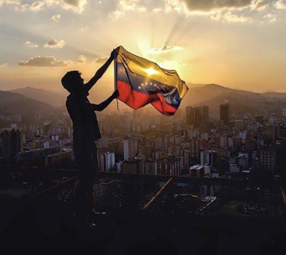 Silueta con bandera venezolana al atardecer sobre Caracas